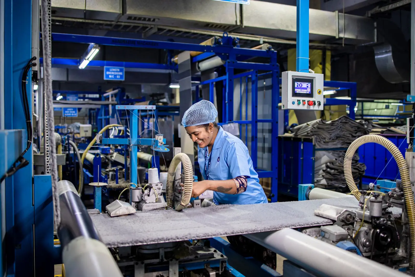 A factory worker operating textile machinery on a production floor