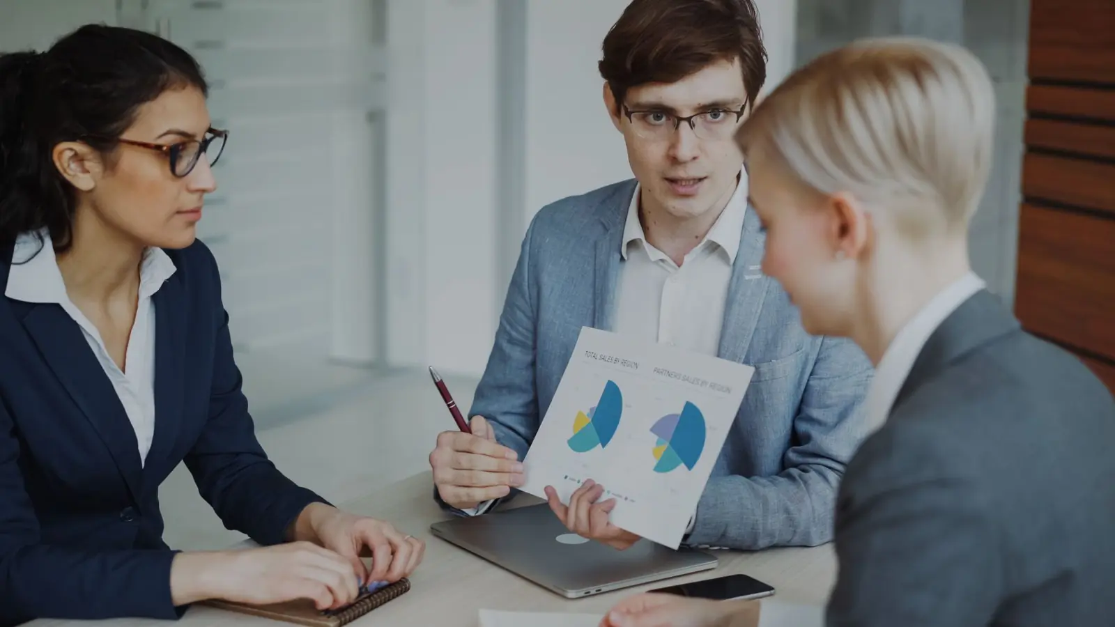 A sales team discussing figures and charts around a meeting table
