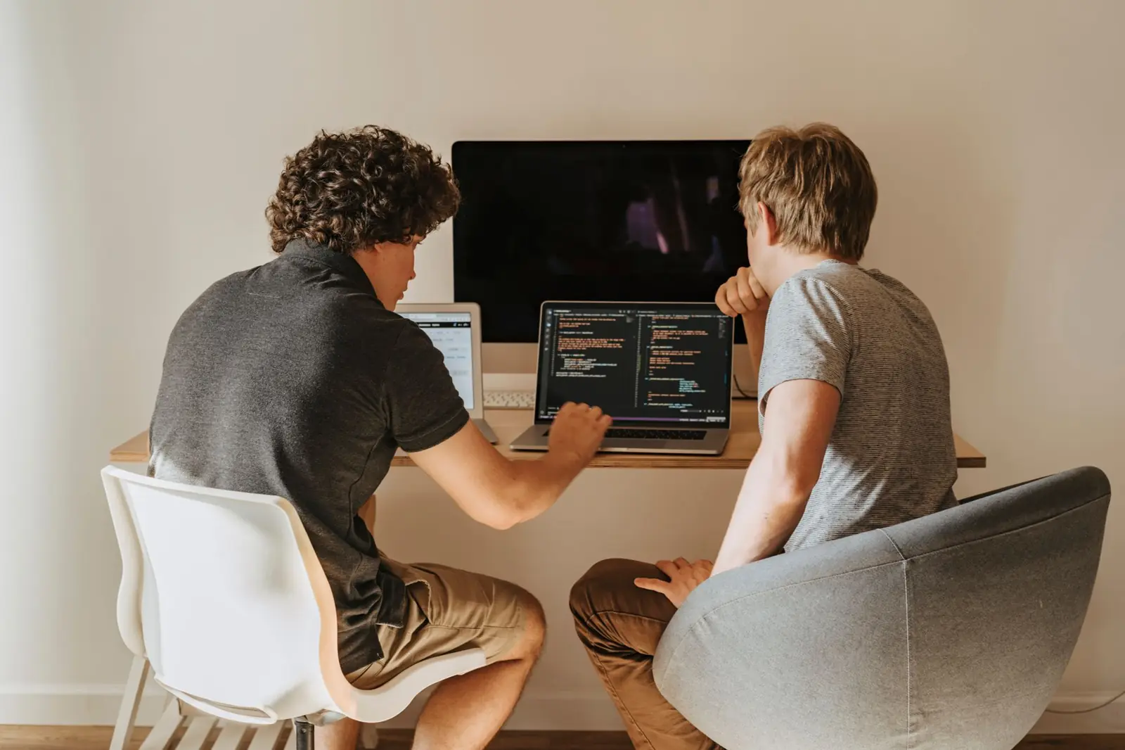 Two software developers working through code together on their laptops
